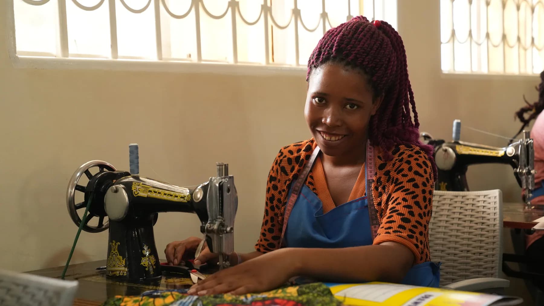 A woman practicing sewing skills at a training center