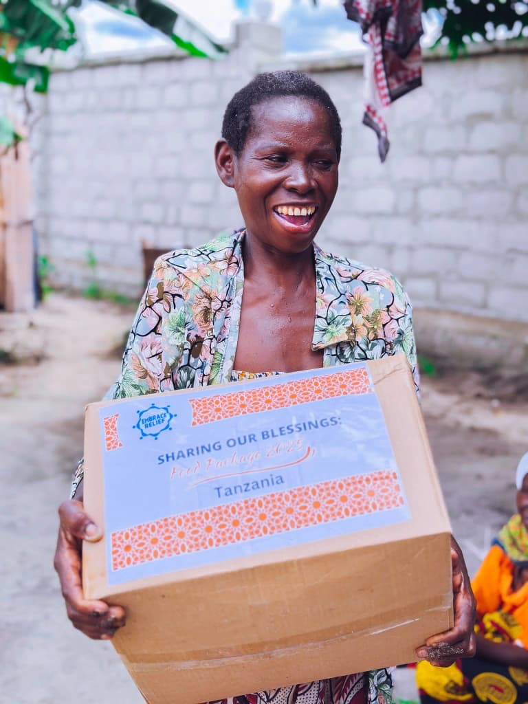 A Tanzania food recipient holding an Embrace Relief package