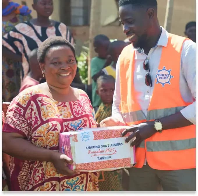 An Embrace Relief volunteer handing a food package to a community member
