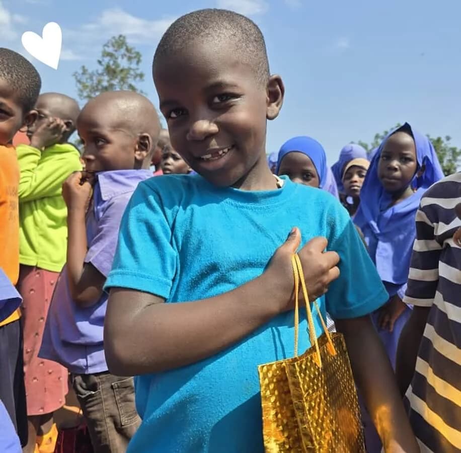A child smiling while holding a birthday gift bag