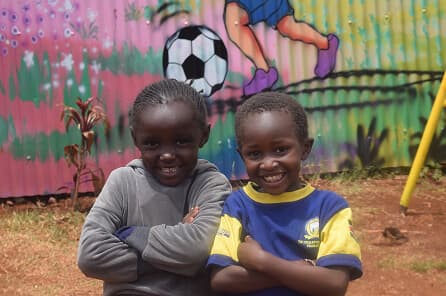 Two children smiling outside their care center