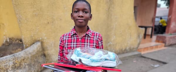 A student holding school supplies provided through orphan care