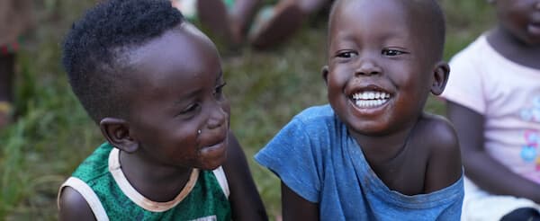 Two smiling children receiving orphan healthcare support