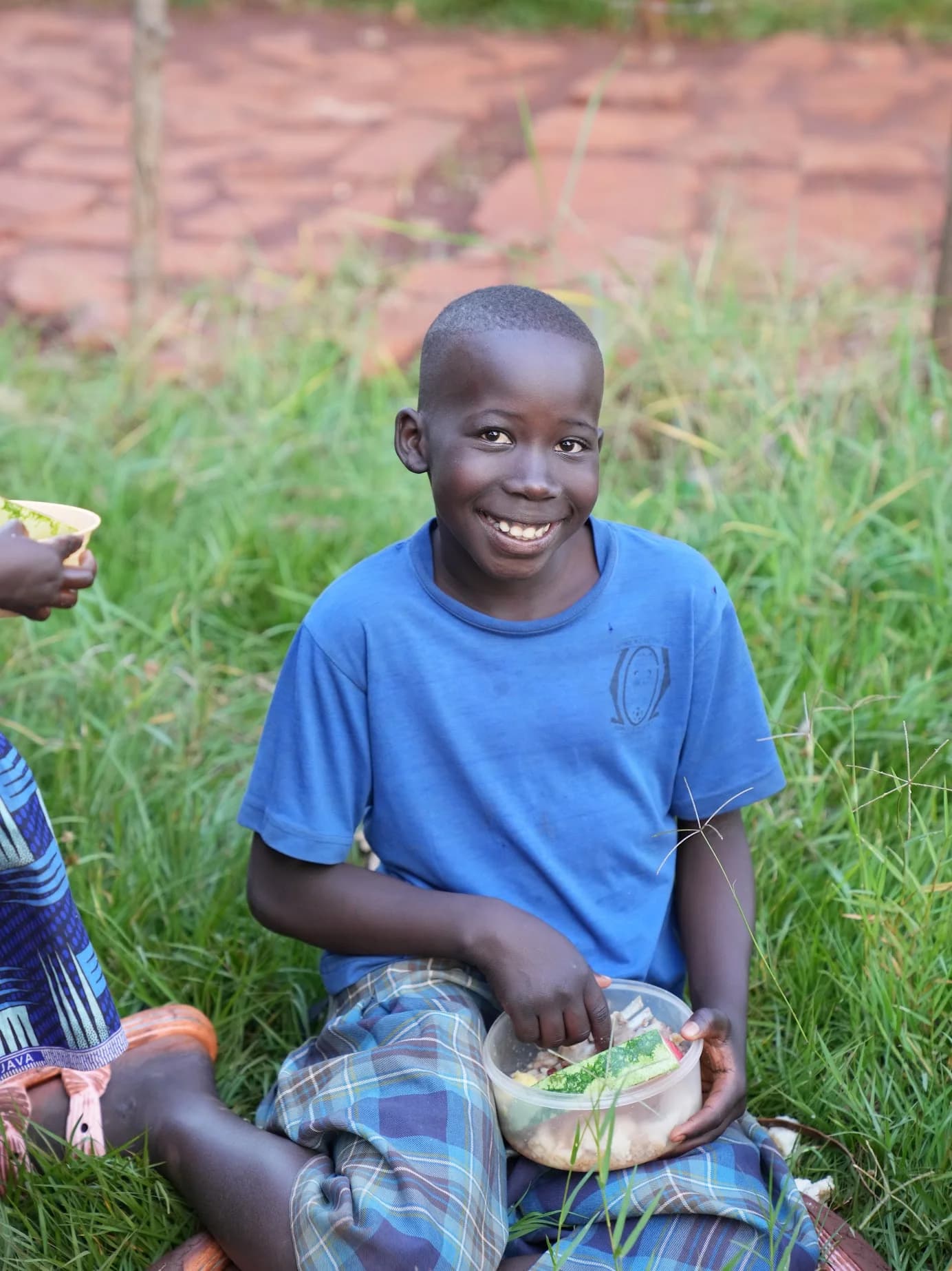 A smiling child sitting outdoors with a meal