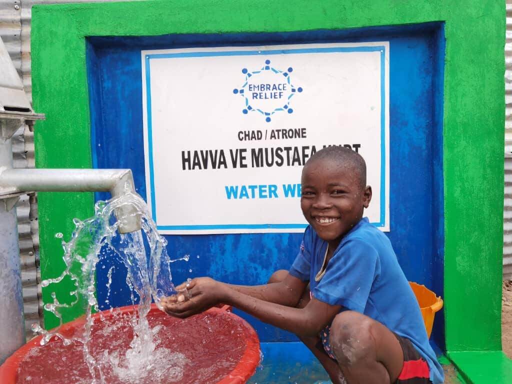 Community members accessing clean water from a well in extreme heat
